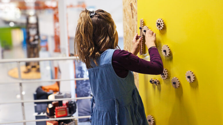 Lapsi tutkimassa Kummituksen keksintökoje -näyttelyä ja kokeilemassa näyttelyssä olevaa mutteriseinää