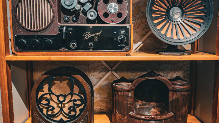 Lähikuva vanhasta radiolaitteistosta, jossa hyllylle on asetettu erilaisia vanhoja radioita eri vuosilta