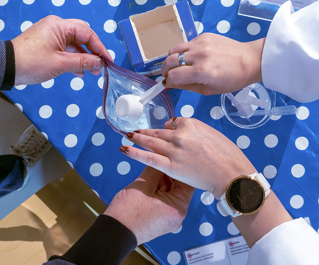 Biomuovi-työpajaan osallistuvien käsiä, jotka valmistavat biomuovia tärkkelyksestä